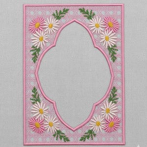 May include: A pink embroidered rectangular design featuring a central open space. The border is adorned with daisies in white, pink, and yellow, along with green leaves. The background has a dotted pattern.