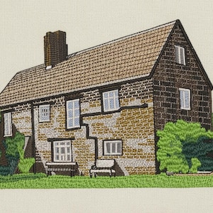 May include: Embroidered artwork of a house with a brown tiled roof, brick walls, and green shrubbery. The house has multiple windows with white frames and a chimney. The artwork is set against a cream-colored background.