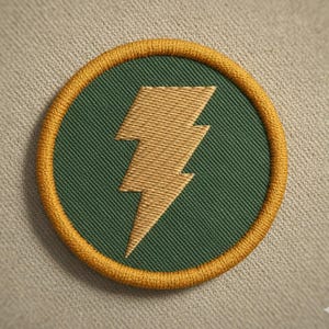 Może przedstawiać: Okrągła, haftowana naszywka ze złotą błyskawicą na zielonym tle, obramowana złotą obwódką. Naszywka jest umieszczona na neutralnej, teksturowanej tkaninie.