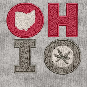 Può includere: Primo piano di un tessuto grigio con lettere e simboli ricamati. Le lettere "OHIO" sono in rosso e grigio, con la "O" che presenta il contorno dell'Ohio e una foglia di ippocastano.