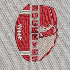 Pode incluir: Design bordado com uma bola de futebol americano vermelha e um capacete, com a palavra "BUCKEYES" exibida verticalmente. O design está em um fundo de tecido cinza. A bola tem detalhes de costura brancos.
