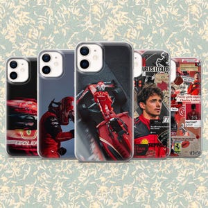 May include: Five phone cases with racing-themed designs. The cases display images of a red race car, a driver in a red racing suit, and a portrait of Charles Leclerc. Some cases have text that reads "LECLER" and "Ferrari".
