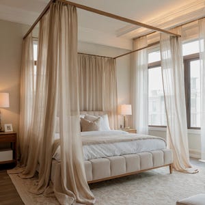 Pode incluir: Uma cama com dossel bege com cortinas transparentes e esvoaçantes. A cama tem uma cabeceira almofadada e uma estrutura de madeira clara. O quarto apresenta grandes janelas com cortinas brancas, um tapete estampado e duas mesas de cabeceira com candeeiros.