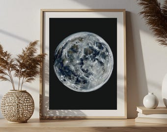 May include: A framed print of the moon, showcasing a detailed, textured surface with shades of gray, white, and blue against a black background. The artwork is displayed in a light-colored wooden frame, adding a touch of natural warmth.