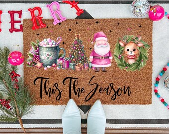 Può includere: Un zerbino marrone a tema natalizio. Presenta una tazza di marshmallow, un albero di Natale, Babbo Natale e una renna. Il testo "This The Season" è scritto in un carattere corsivo. Ornamenti e ghirlande decorano il tappeto.