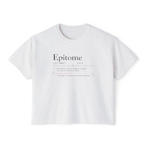 May include: A white short-sleeved t-shirt featuring black and pink text that defines the word Epitome. The graphic includes the phonetic spelling, a noun label, a dictionary definition, and the phrase, the biggest, the epitome of testing connections.