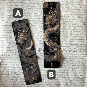 以下が含まれることがあります： 金色の龍の模様が施された2つの黒いブックマーク。ブックマークAは、金色のアクセントが付いた灰色の背景に龍がいます。ブックマークBは、金色のアクセントが付いた黒い背景に龍がいます。どちらも長方形です。