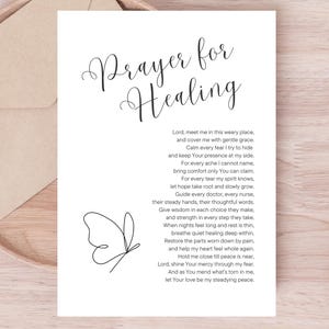 May include: A white card with the words "Prayer for Healing" in elegant script, accompanied by a poem and a butterfly illustration. The card is placed on a wooden tray with a neutral-toned envelope.