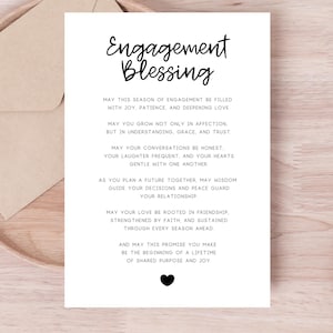May include: A white engagement card with black script, featuring the words "Engagement Blessing" and a heartfelt message. The card is placed on a wooden tray with a beige envelope, perfect for a wedding or engagement gift.