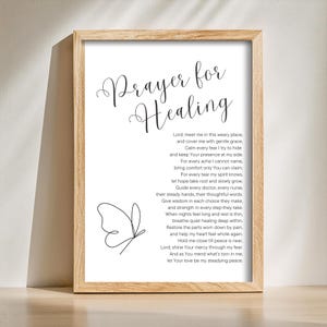 Può includere: Stampa incorniciata con le parole "Prayer for Healing" in elegante scrittura. La stampa include una poesia e un'illustrazione di farfalla nera su sfondo bianco. La cornice è in legno chiaro.