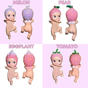 K&ouml;nnte beinhalten: Vier kleine, nacktfarbene Figuren mit Obst-Themen-Kopfbedeckungen. Die Fr&uuml;chte sind mit "Melone", "Birne", "Aubergine" und "Tomate" beschriftet. Jede Figur hat einen einzigartigen Gesichtsausdruck und eine einzigartige Pose mit glitzernden Details auf der Frucht.