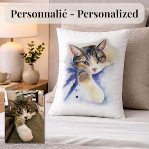 Peut inclure: Coussin carré blanc avec une peinture à l'aquarelle d'un chat aux yeux verts, au pelage brun, noir et blanc. Le coussin est posé sur un lit avec une tête de lit aux tons neutres et une table de chevet avec une lampe et un vase.