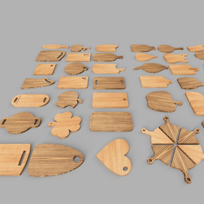 Op de afbeelding: Een verzameling verschillende houten snijplanken in verschillende vormen en maten. De planken omvatten rechthoekige, ovale en uniek gevormde ontwerpen zoals een hart en een klavertjevier. De houtnerf is zichtbaar en de planken zijn gerangschikt op een grijze ondergrond.