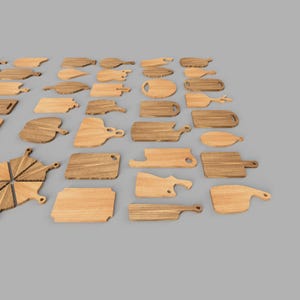 Op de afbeelding: Een verzameling houten snijplanken in verschillende vormen en maten. De planken zijn gemaakt van lichtbruin hout met zichtbare nerfpatronen. Sommige hebben handvatten, andere unieke uitsparingen.