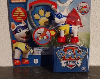 May include: A Paw Patrol Apollo the Super Pup action figure in a blue and red package. The figure is white with a blue mask, yellow vest, and red boots. The packaging includes the Paw Patrol logo and the Nickelodeon logo.