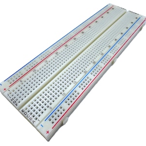 May include: A white breadboard with numerous holes for electronic components. It features red and blue lines along the edges, with numbers and letters printed on the surface. The breadboard is designed for prototyping and circuit design.