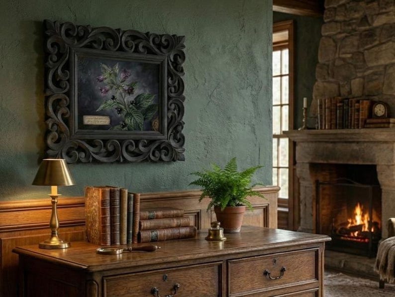 May include: A dark wooden desk with a brass lamp, books, and a fern in a terracotta pot. A framed botanical print hangs on the green wall. A fireplace with a burning fire is in the background.