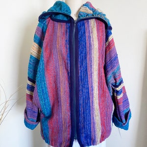 May include: A colorful striped hooded jacket with a zipper closure. The jacket is made of a soft, woven fabric and has a relaxed fit.