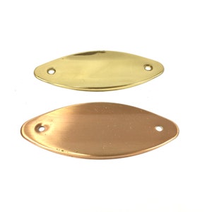 May include: Two metal oval-shaped plates with two holes each. One plate is gold-colored, and the other is copper-colored. The plates are on a white background.