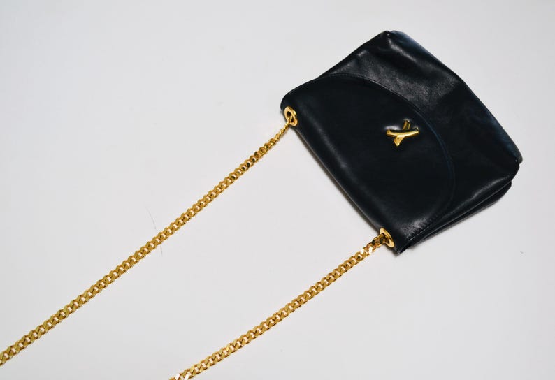 May include: A black leather shoulder bag with a gold chain strap and a gold accent on the flap.