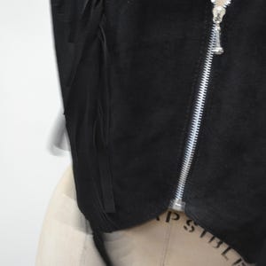 May include: Black suede vest with fringe detailing and a zipper closure.