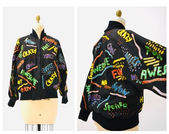 May include: A black bomber jacket with colorful embroidered text, including "Cool", "Awesome", "Crazy", "Nuts", "How", "Spoiled", and "FW".