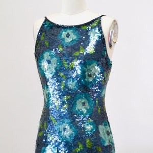 May include: A sleeveless sequined dress with a floral pattern in shades of blue and green.