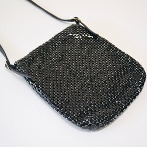 May include: A black chainmail crossbody bag with a long black strap.
