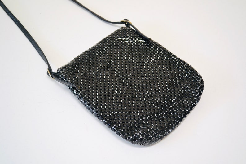 May include: A black chainmail crossbody bag with a long black strap.