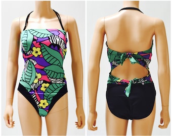 May include: A black and green swimsuit with a tropical leaf and zebra print. The swimsuit has a halter neck strap and a tie back.