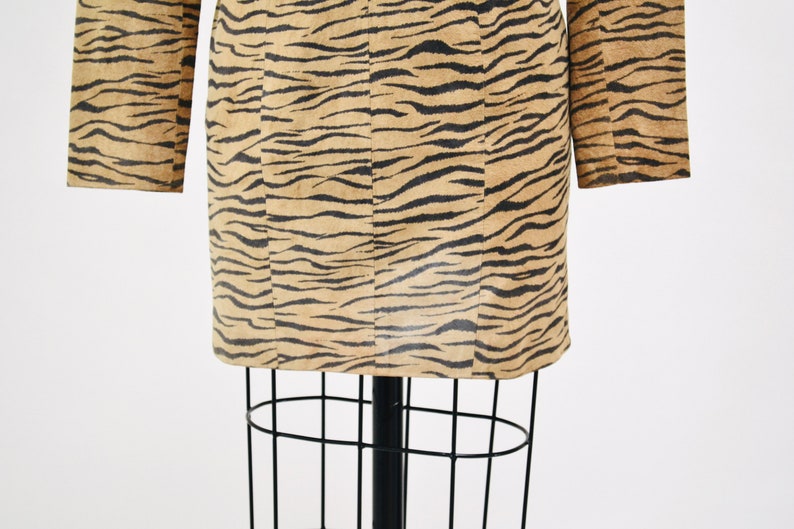 Op de afbeelding: Een mini-jurk met lange mouwen in een bruine en zwarte tijgerprint.