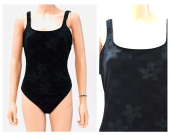 May include: Black one-piece swimsuit with a floral pattern. The swimsuit has thin straps and a scoop neck.