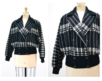 May include: A black and white plaid cropped jacket with a double breasted closure and a black ribbed waistband.