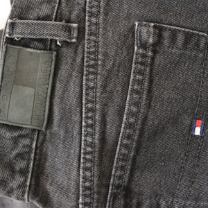 May include: A pair of dark gray denim jeans with a Tommy Hilfiger label and a small red, white, and blue logo patch on the back pocket.