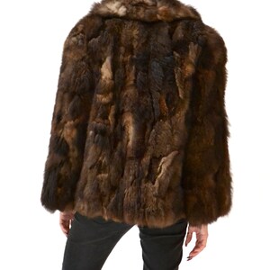 May include: A brown rabbit fur coat with a collar. The coat is worn by a person, but the person is not visible in the image.
