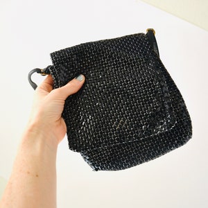 May include: A black mesh chain bag with a short strap. The bag is made of small, shiny, black squares.