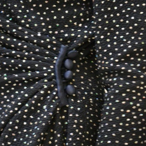 May include: A black dress with a sparkly, textured fabric and a navy blue trim with buttons.