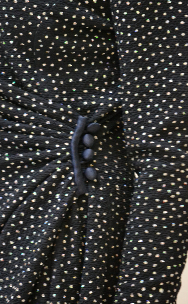 May include: A black dress with a sparkly, textured fabric and a navy blue trim with buttons.