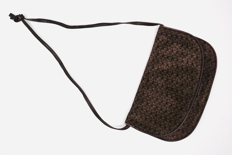 May include: A brown leather shoulder bag with a black and brown patterned design. The bag has a long strap and a flap closure.