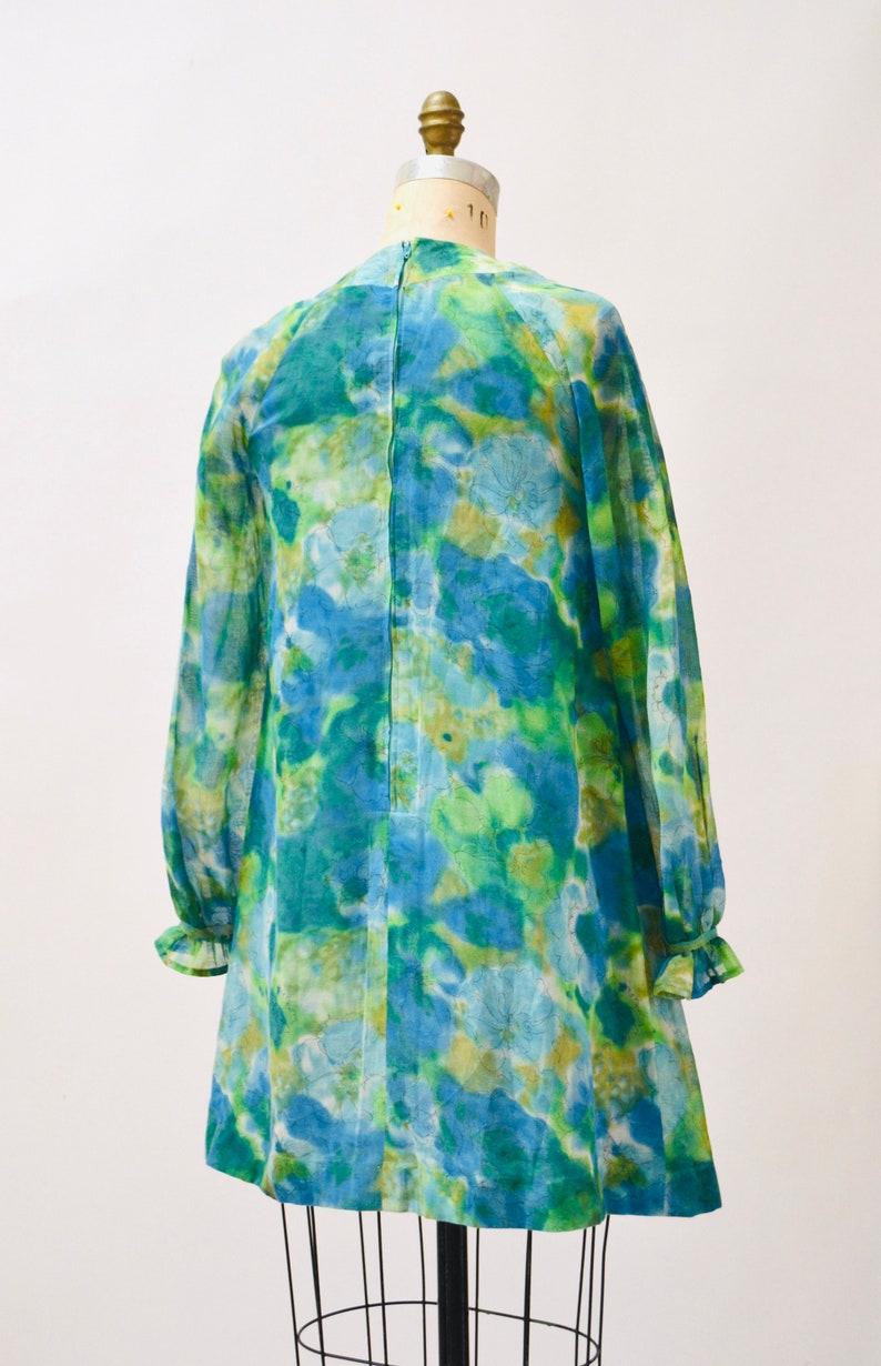 May include: A blue and green floral print mini dress with long sleeves and a ruffled hem.