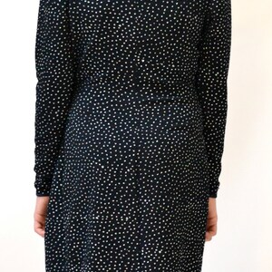 May include: A black long-sleeved dress with a sparkly, all-over pattern. The dress has a V-neckline and a fitted silhouette.