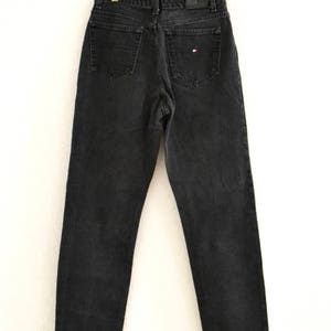 May include: Black denim jeans with a small red, white, and blue logo on the back pocket.