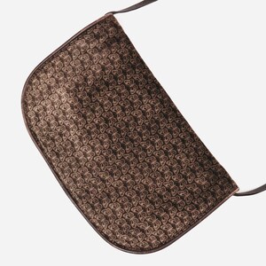 May include: A brown suede shoulder bag with a butterfly pattern. The bag has a long strap and a flap closure.