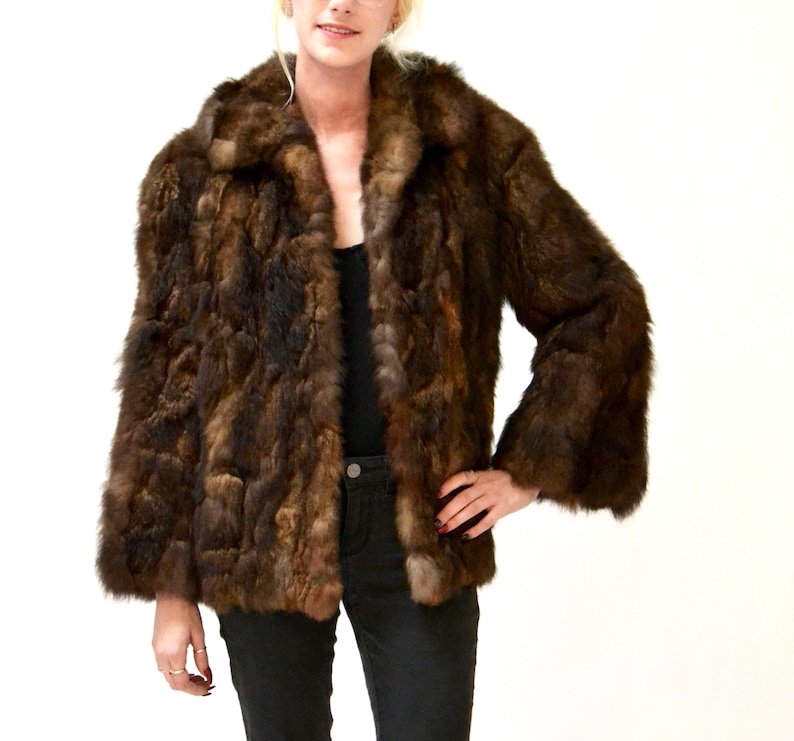 May include: A brown fur jacket with a long sleeve and a collar. The jacket is made of a soft, fluffy fur.