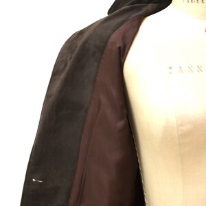 May include: A brown suede coat with a brown satin lining. The coat is open and the lining is visible.