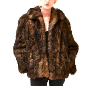 May include: A brown fur jacket with a collar. The fur is a mix of light and dark brown.