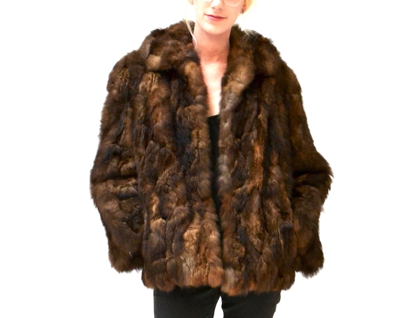 May include: A brown fur jacket with a collar. The fur is a mix of light and dark brown.