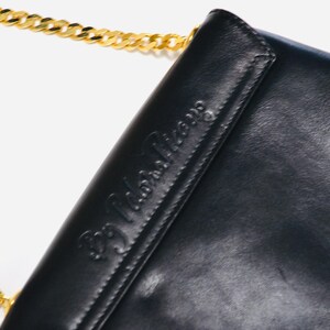 May include: Black leather shoulder bag with a gold chain strap and the embossed text "BB John Paris".