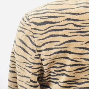 Op de afbeelding: Een bruin su&egrave;de jack met een zwart en bruin zebraprint.