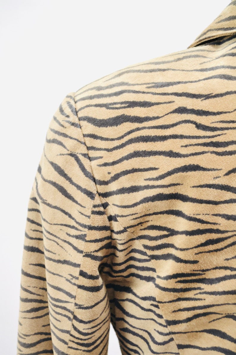 Op de afbeelding: Een bruin su&egrave;de jack met een zwart en bruin zebraprint.